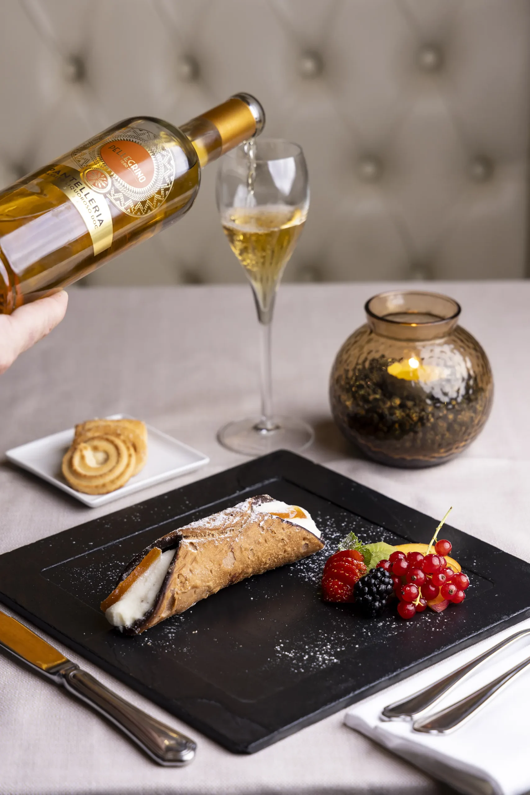 Un piatto con un cannolo siciliano e dei frutti di bosco